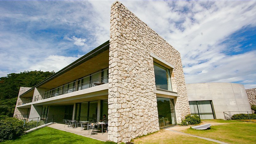 Stone and glass wing of Benesse House above the lawn on Naoshima, Japan