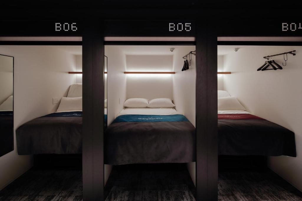 Three numbered sleeping capsules along a corridor at The Millennials, Kyoto
